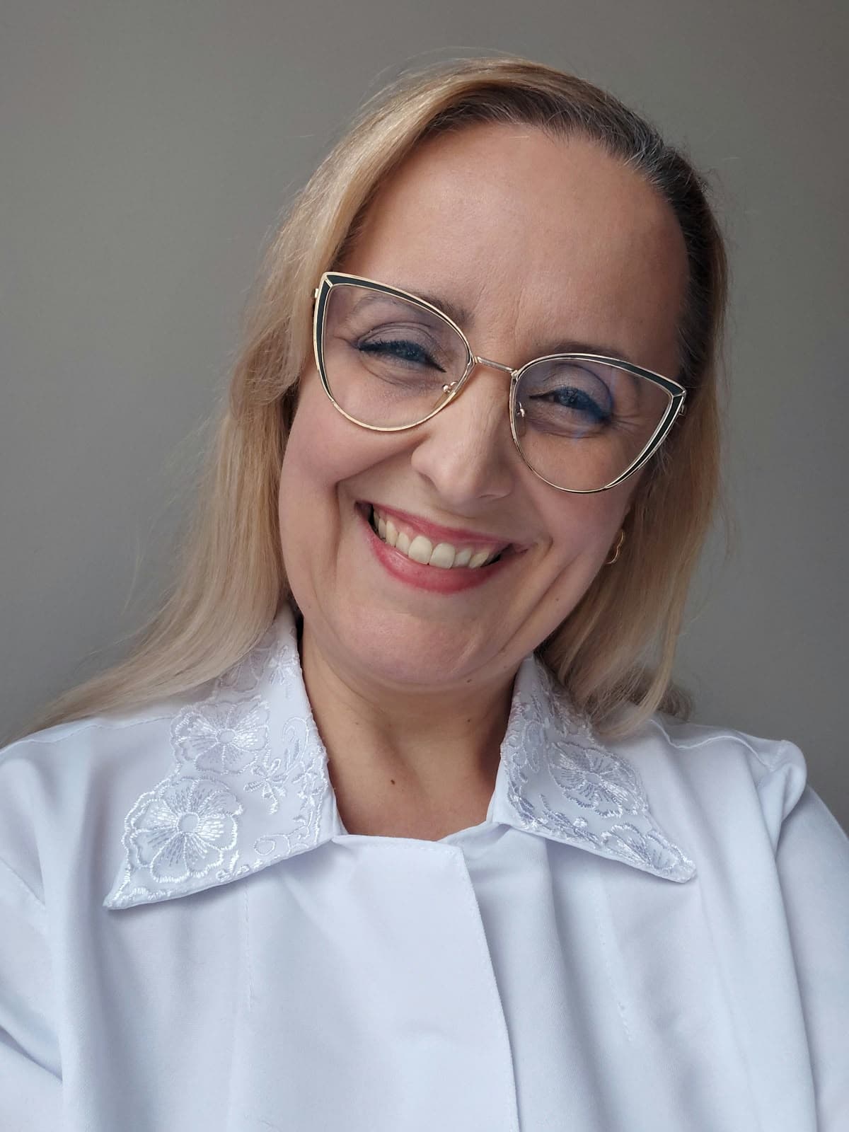 Monica Boeira, fonoaudióloga, sorrindo, de jaleco branco